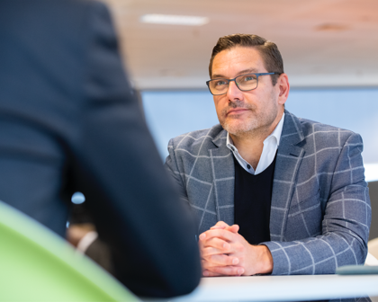 Masasında karşısındakini dinleyen gözlüklü bir erkek