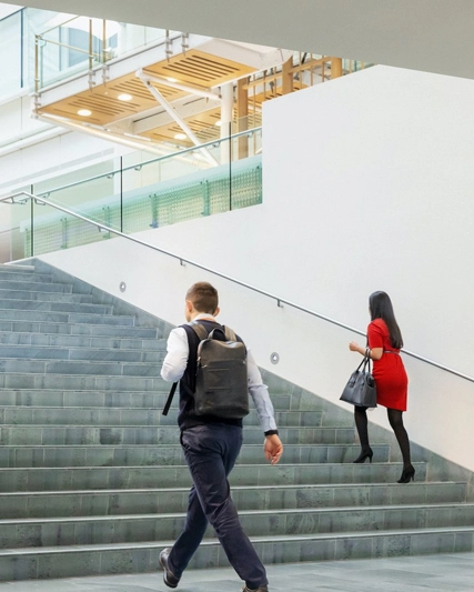 Merdivenlerde yukarı ve aşağı yönde ilerleyen insanlar, birbiriyle konuşan bir kadın ve erkek